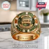 Gold Jeep 85th anniversary ring with green gemstone, diamond accents, and etched text on a marble surface.!