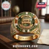 Gold Jeep 85th anniversary ring featuring green center stone, encrusted diamonds, and engraved text on a leather desk.!