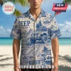 Man wearing a blue and beige patterned short-sleeve shirt with Jeep off-road graphics, trail signs, and mountain scenes.!