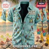 Light blue denim short-sleeve shirt with parrot, margarita, burger, and sailboat patches over a tropical beach background.!