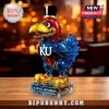 Kansas Jayhawks mascot shaped glass liquor decanter with red, blue, and gold accents on a wood table surface.!