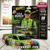 Kyle Busch M&M's Toyota Camry Hot Wheels die-cast car and blister pack with green racing suit graphic on wood background.!
