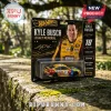 Kyle Busch Hot Wheels legacy memorial diecast car in yellow M&M racing livery on a cardboard backing in a park setting.!