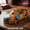M&M branded Toyota Camry race car shaped glass decanter with a gold metal cap sitting on a wooden desk.!