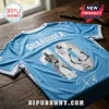 Manchester City light blue football jersey featuring Pep Guardiola text, trophy graphics, and signature on wooden desk.!