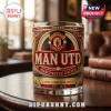 Manchester United whiskey glass with gold, red, and black crest, glittered lettering, and Est. 1878 date on wood table.!