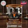 McLaren Racing 1000th Formula 1 Grand Prix whiskey glass featuring an orange and black race car graphic on a wooden desk.!
