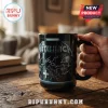 Black ceramic coffee mug featuring Metallica logo, silver chains, and skull graphic on a wooden table.!