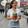 Woman holding a green and red soccer-themed drink canister with a trophy topper and white plastic straw on a city street.!