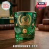Green glass whiskey tumbler with gold Mexico World Cup 2026 emblem, Aztec mask relief, and stadium graphics on wood table.!
