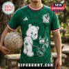 Green Mexico soccer jersey featuring a cartoon bear graphic, FIFA branding, and national flag icons held by a person.!