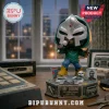 MF DOOM vinyl figure holding a microphone on a 30th-anniversary base, featuring a silver gladiator mask and green hoodie.!