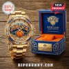 New York Knicks gold-tone wristwatch with diamond-encrusted bezel and branded blue leather display box on wooden surface.!