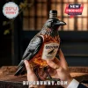 Raven-shaped glass whiskey decanter with Old Crow label being held in two hands over a wooden table.!