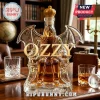 Ozzy Osbourne shaped glass decanter with a golden crown topper filled with amber liquor on a dark wood desk.!