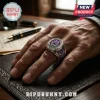 Silver gothic ring with purple enamel, bat motifs, and crystal accents worn on a man's finger over a leather desk pad.!