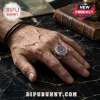 Silver signet ring with a purple enamel center featuring a skull emblem on a man's finger, set against black marble.!