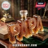 PAPA shaped glass whiskey decanter with amber liquid and intricate floral etching on a wooden desk with vintage books.!