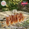 PAPA shaped glass decanter filled with amber liquid, featuring intricate etched thistle patterns on a stone outdoor table.!