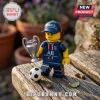 Paris Saint-Germain minifigure wearing a team cap and jersey, holding a silver Champions League trophy near a toy soccer ball.!