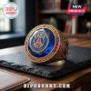 Paris Saint-Germain gold championship ring with a large blue center stone, red and blue side accents, on a slate base.!