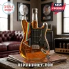 Guitar-shaped glass decanter filled with amber liquid featuring a prism and rainbow graphic on a wooden table surface.!