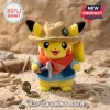 Pikachu plush toy wearing a tan explorer hat, blue vest, and red neckerchief holding a small plastic pickaxe in sand.!