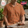 Man wearing a burnt orange short-sleeve shirt with a teal and yellow diamond ikat pattern at a wooden outdoor table.!