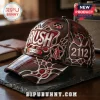 Deep red Rush band baseball cap with 3D chrome-style tribal accents, 1968-2027 text, 2112 logo, and Starman icon on table.!
