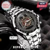 Slayer band metal wristwatch with eagle logo, silver link bracelet, tachymeter bezel, and black dial resting on camera lens.!