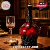 Deep red glass whiskey decanter with ornate black filigree metal casing and crown stopper next to a crystal glass.!