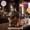 Skull-shaped glass whiskey decanter with ornate antique silver metal filigree overlay and crown stopper on a bar counter.!