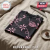 Black and pink Hummel football jersey with floral patterns and a soccer club crest, folded on a beige textured fabric.!