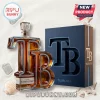 Tampa Bay themed glass whiskey decanter shaped like TB letters next to a blue presentation box on sandy beach background.!