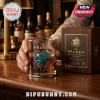 The Kraken whiskey glass with a metallic teal octopus and ship emblem, placed next to a wooden presentation box on a bar.!