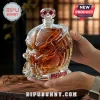 Predator helmet shaped glass liquor decanter filled with amber spirit, held in hands over a wooden surface.!