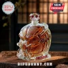 Predator helmet glass whiskey decanter filled with amber liquid, resting on a wooden surface with a crystal stopper.!