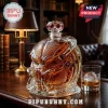 Predator helmet shaped glass decanter filled with amber whiskey, featuring a faceted crystal stopper on a wooden desk.!