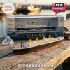 1:64 scale die-cast metal RMS Titanic model ship with four yellow smokestacks on a wooden pier next to its display box.!