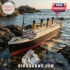 Titanic model cruise ship resting on rocky shore near water with a transparent crystal fragment in the foreground.!