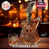 U2 50th anniversary guitar-shaped glass whiskey bottle with Zoo TV etching and a matching crystal tumbler on wood table.!
