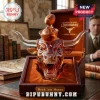 Amber glass longhorn steer decanter with a football-shaped stopper in a branded display case on a mahogany desk.!