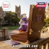 Faceted purple glass husky shaped decanter in a dark wood case with a gold W logo, set against a college campus background.!