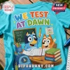 Bright turquoise t-shirt featuring Bluey characters at a desk with textbooks, a chalkboard, and text We Test At Dawn.!