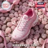 Pink Nike Air Max Plus sneaker with breast cancer awareness ribbon icons, resting on smooth rose quartz stones and ribbons.!