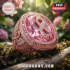 Rose gold ring with a large pink gemstone, breast cancer awareness ribbon, and engravings on a mossy log background.!
