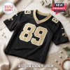 New Orleans Saints black football jersey with gold number 89, NFL logo on neckline, on a marble table with white cloth.!