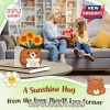 Crocheted brown bear holding three yellow sunflowers and a small sign with text about making the world a better place.!