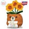 Crocheted brown bear plush holding a sign with yellow sunflower accents and inspirational text on a white background.!