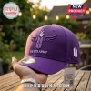 BTS Army Purple Embroidered Logo Baseball Cap featuring a hand finger heart, wings, and text on a blurred garden background.